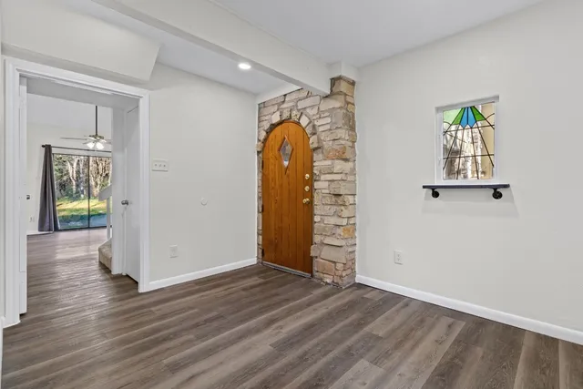 an empty room with wooden floor and windows