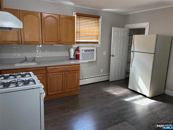 a kitchen with a refrigerator a stove a sink wooden floor and cabinets