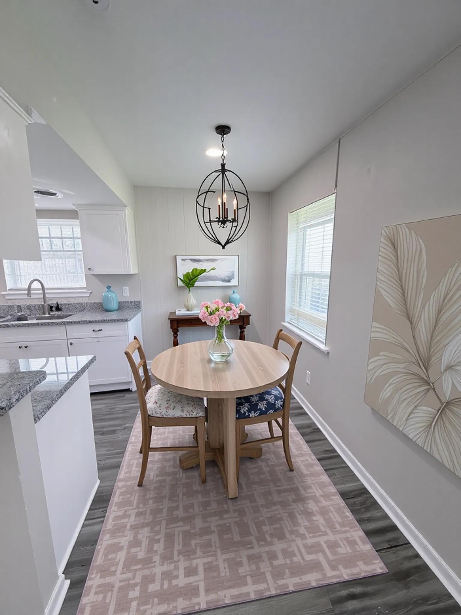 7705 Parker Road Houston, TX 77016 - Photo 6 of 17 a dining room with wooden floor a chandelier a wooden table and chairs