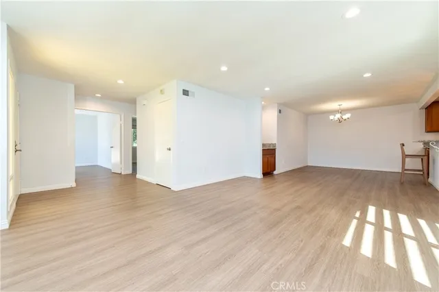 a kitchen with stainless steel appliances granite countertop wooden cabinets a sink a stove a refrigerator with wooden floor and a window