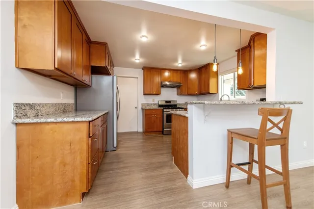a kitchen with granite countertop wooden cabinets a sink and dishwasher with wooden floor
