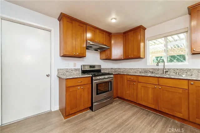 a kitchen with stainless steel appliances granite countertop a stove a refrigerator and a wooden cabinets