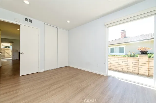 a view of an empty room with wooden floor and closet