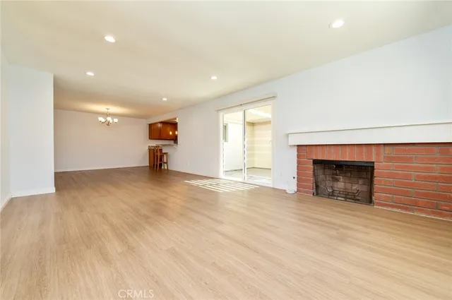 an empty room with wooden floor fireplace and windows
