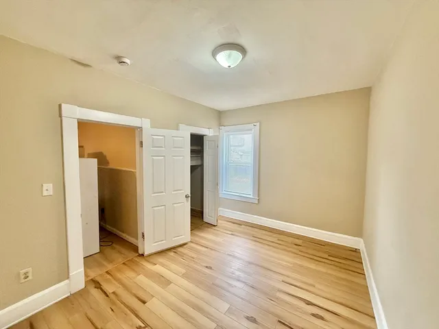 a view of an empty room with wooden floor and closet