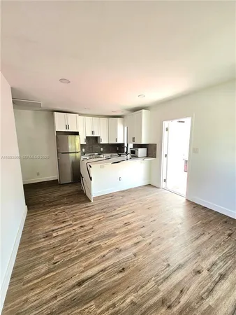 a view of a kitchen with a sink wooden cabinets and a refrigerator