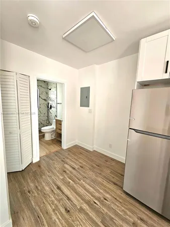 a view of a room with wooden floor and a refrigerator