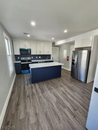 a kitchen with stainless steel appliances granite countertop a stove a refrigerator a sink dishwasher and a oven with wooden floor