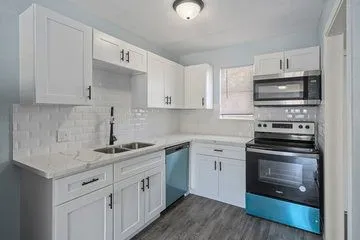 a kitchen with cabinets stainless steel appliances a sink and a stove