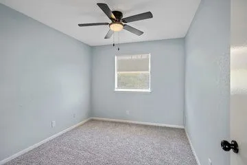 an empty room with a window and a fan
