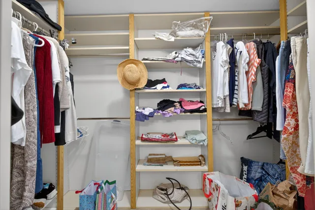 a view of walk in closet with clothes and shoes