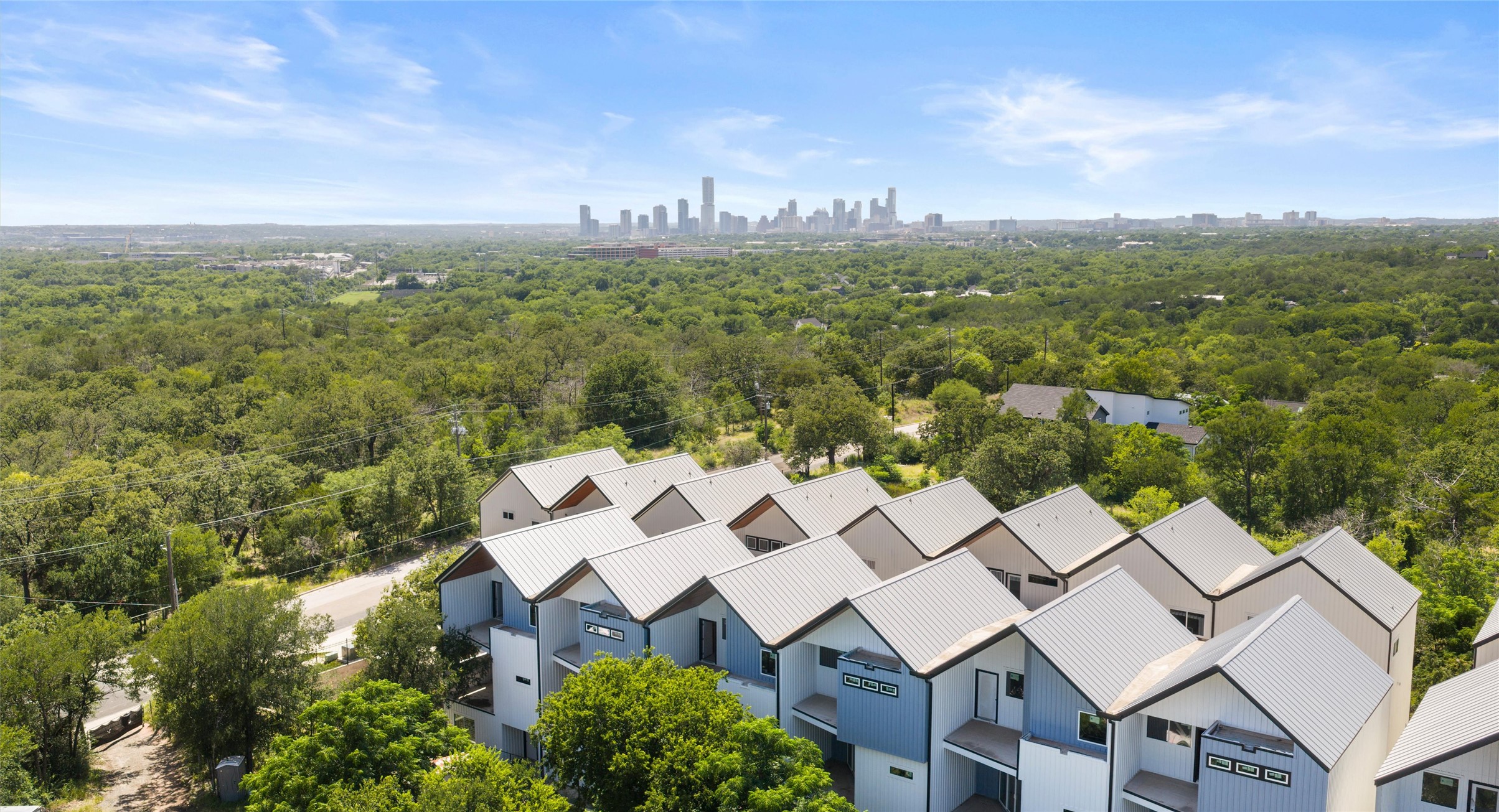 5912 Harold Court, Unit 107 Austin, TX 78721 - Photo 6 of 35 Mature trees frame the community, lending privacy and a calm, natural setting close to central Austin. Model No. 105 Shown.