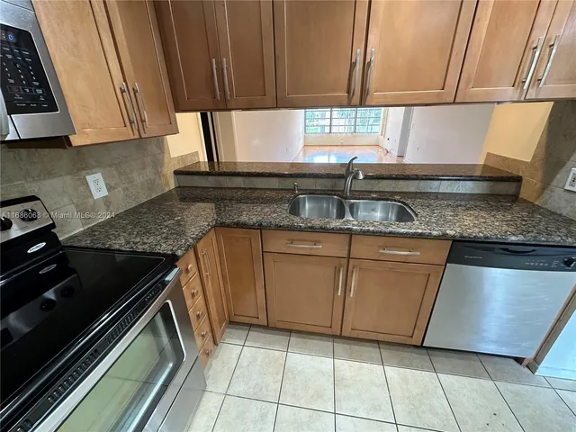 a kitchen with granite countertop a sink stove and cabinets