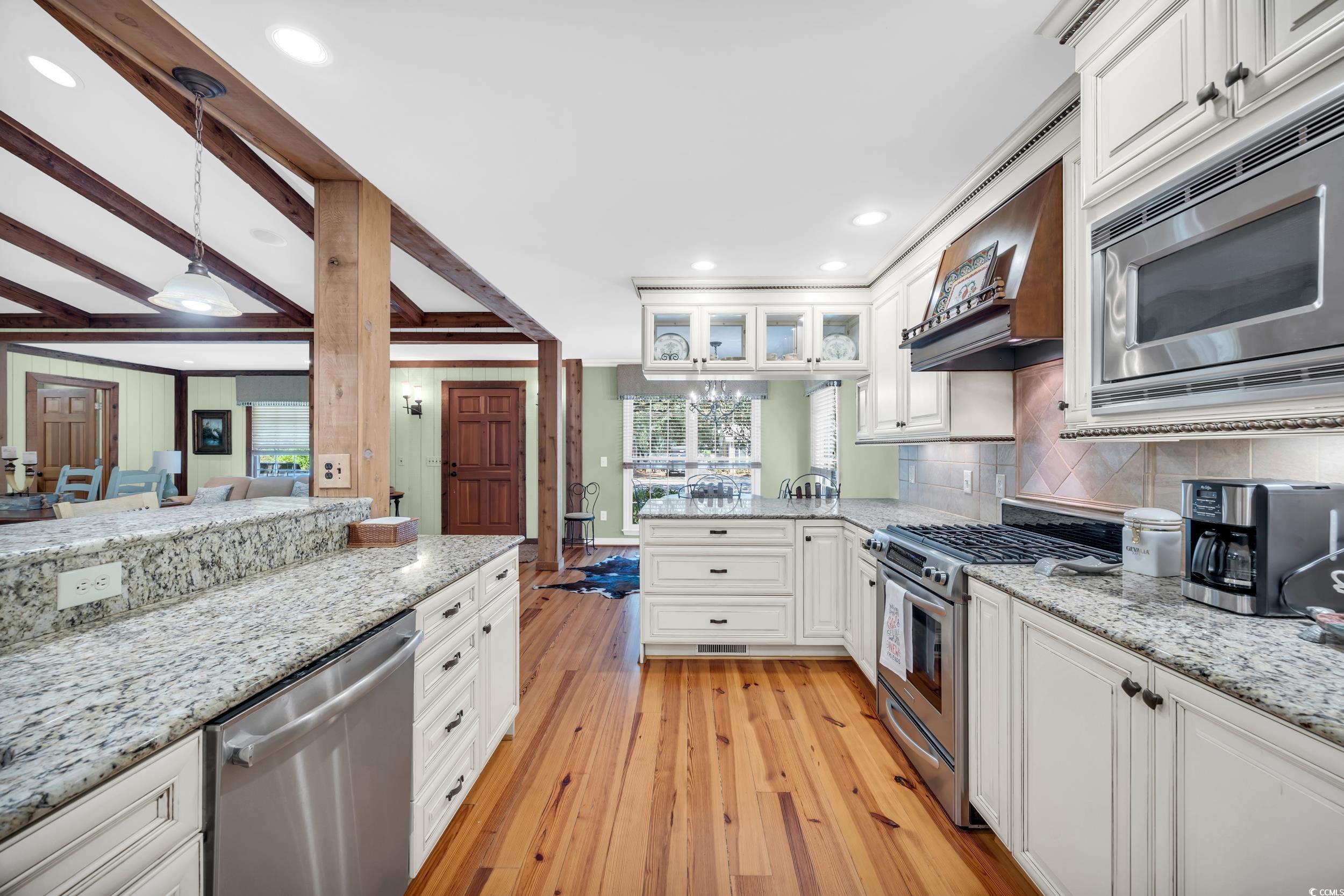 855 Riven Oak Drive Murrells Inlet, SC 29576 - Photo 10 of 37 Kitchen with white cabinets, light stone countertops, appliances with stainless steel finishes, hanging light fixtures, and light wood-style flooring