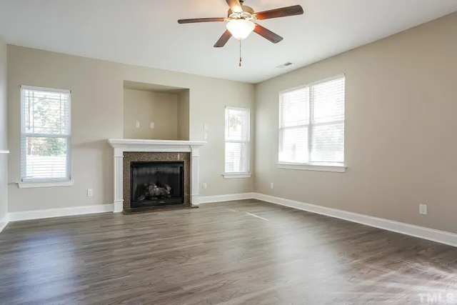 an empty room with windows fireplace and wooden floor