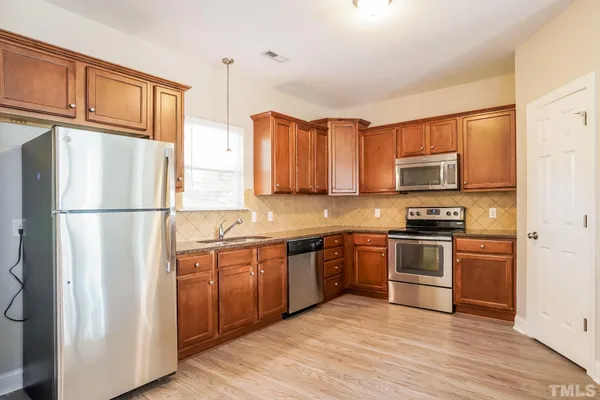 a kitchen with stainless steel appliances granite countertop a refrigerator stove top oven and sink