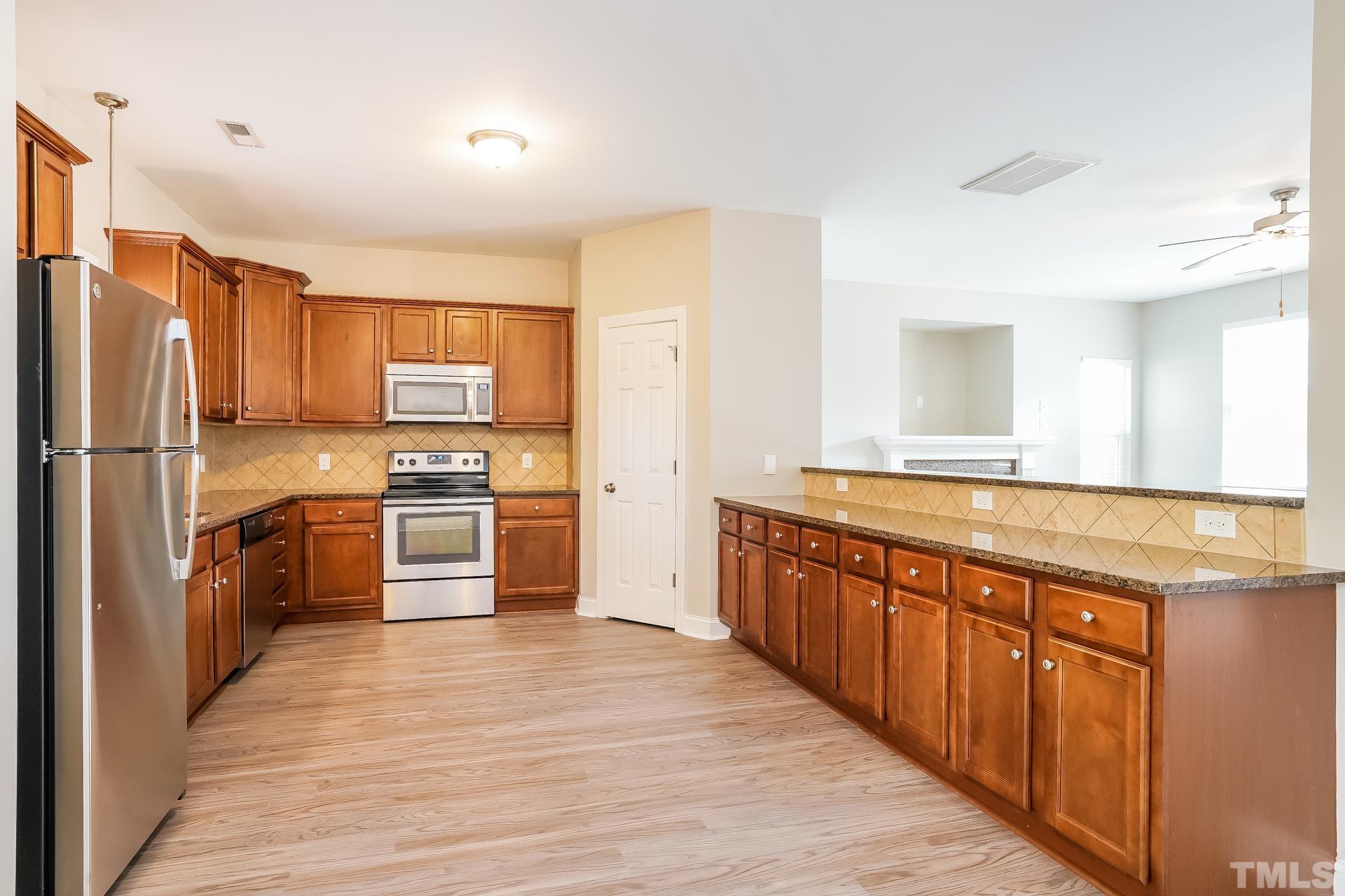 49 Burrage Drive Angier, NC 27501 - Photo 8 of 17 a large kitchen with cabinets wooden floor and stainless steel appliances
