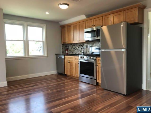 140 Prospect Street, Unit 2 Garfield, NJ 07026 - Photo 2 of 12 a kitchen with wooden floors and stainless steel appliances