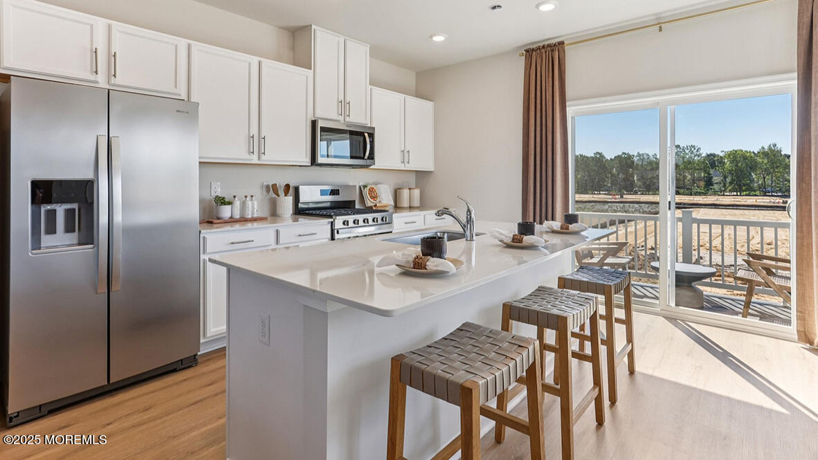 a kitchen with kitchen island a large window appliances and cabinets