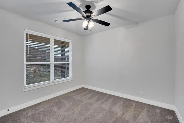 an empty room with window and ceiling fan