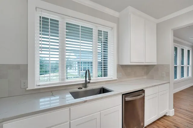 a kitchen with granite countertop a sink window and cabinets