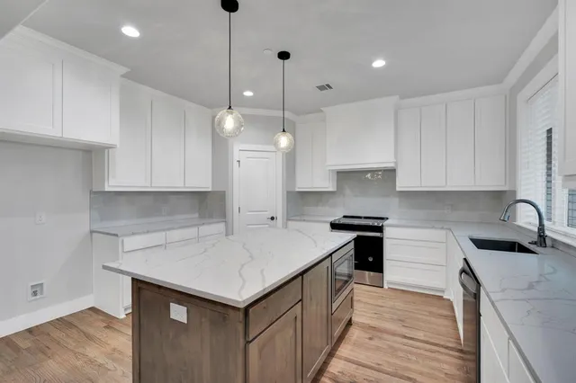 a kitchen that has a lot of cabinets in it with granite countertop stainless steel appliances