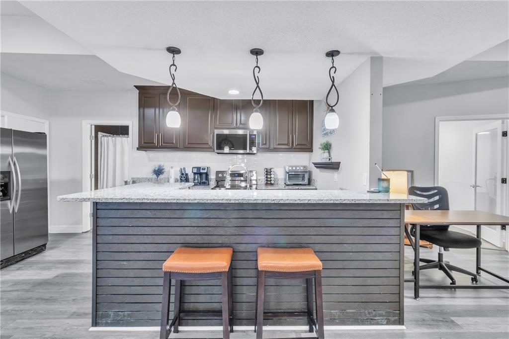 5483 Wylstream Way Norcross, GA 30093 - Photo 37 of 56 a kitchen with stainless steel appliances kitchen island granite countertop wooden cabinets a sink dishwasher and a stove