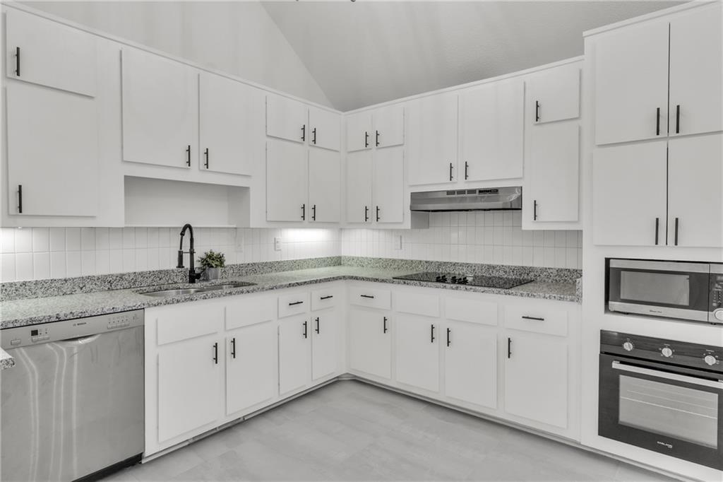 5483 Wylstream Way Norcross, GA 30093 - Photo 7 of 56 a kitchen with granite countertop white cabinets and stainless steel appliances