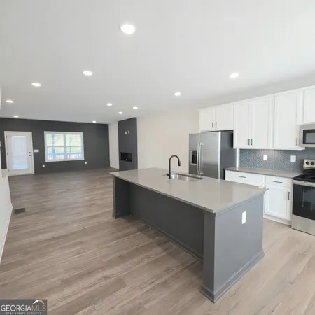 a large kitchen with stainless steel appliances a large counter top a stove and a wooden floors