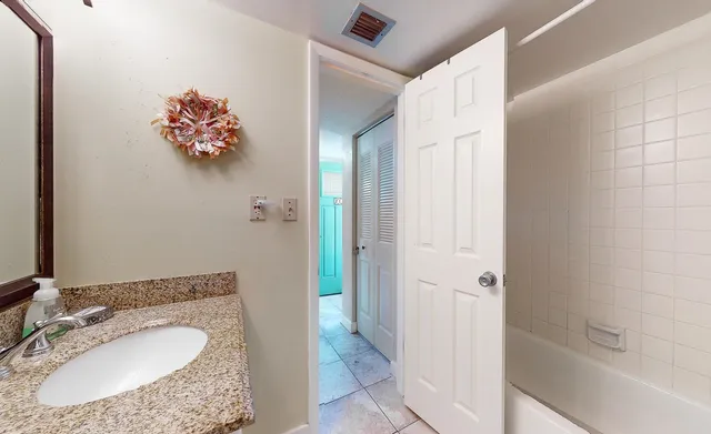 a bathroom with a granite countertop sink vanity mirror and toilet