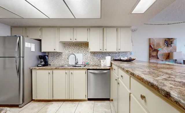 a kitchen with granite countertop stainless steel appliances a refrigerator a sink and white cabinets