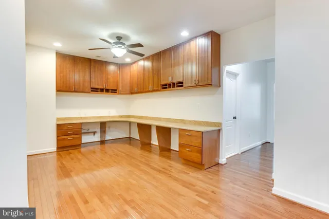 a living room with kitchen island a wooden floor and a ceiling fan
