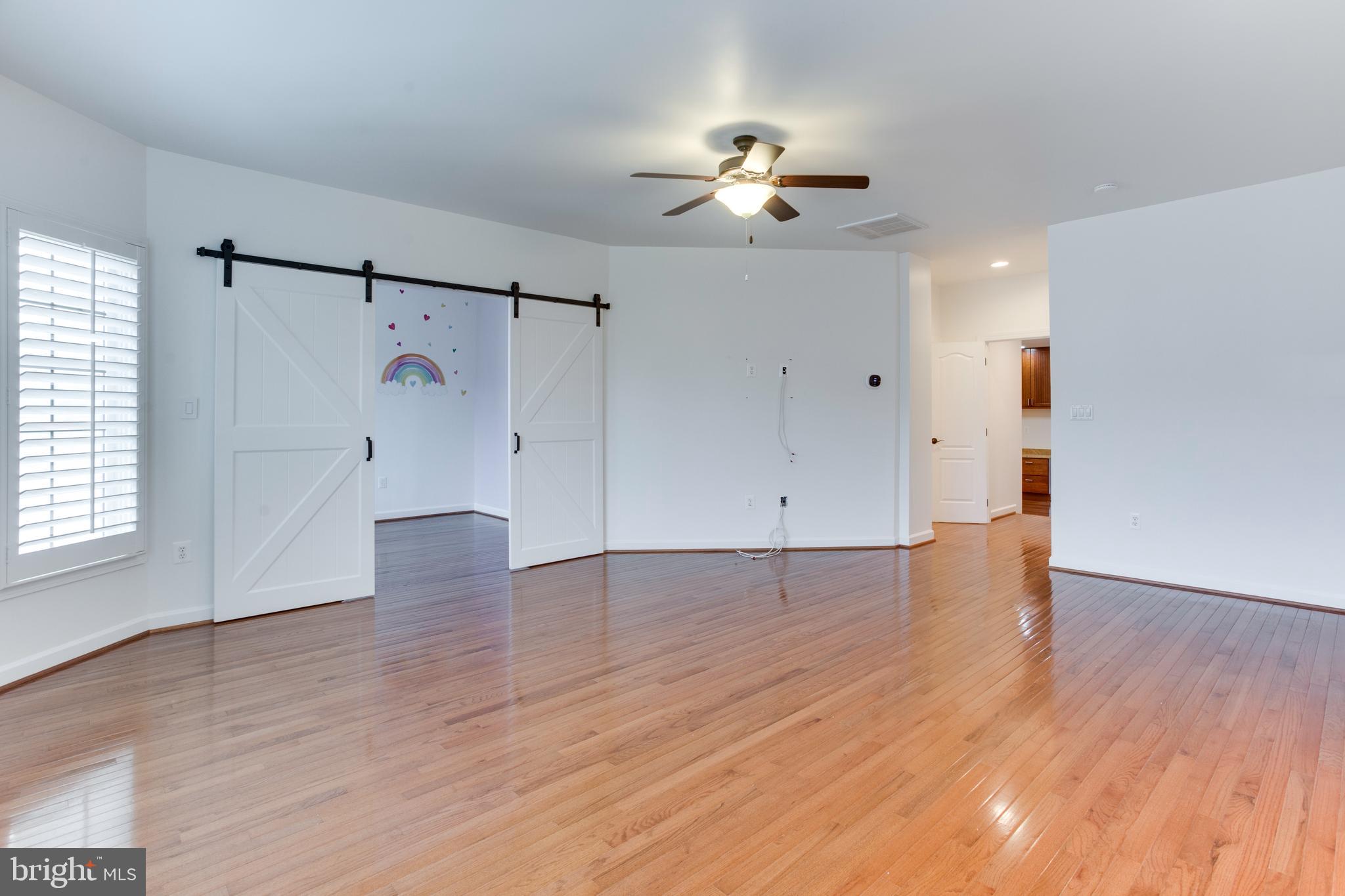 18353 Fairway Oaks Square Leesburg, VA 20176 - Photo 41 of 50 an empty room with wooden floor chandelier fan and windows