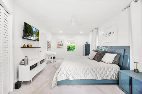 a spacious bedroom with a bed and a flat screen tv