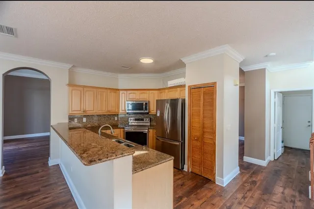 a kitchen with stainless steel appliances granite countertop a refrigerator a stove and a wooden floors