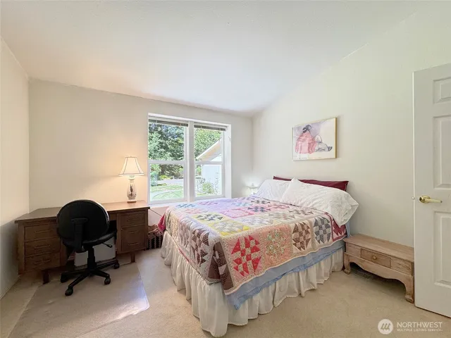 a bedroom with a bed and a lamp on dresser