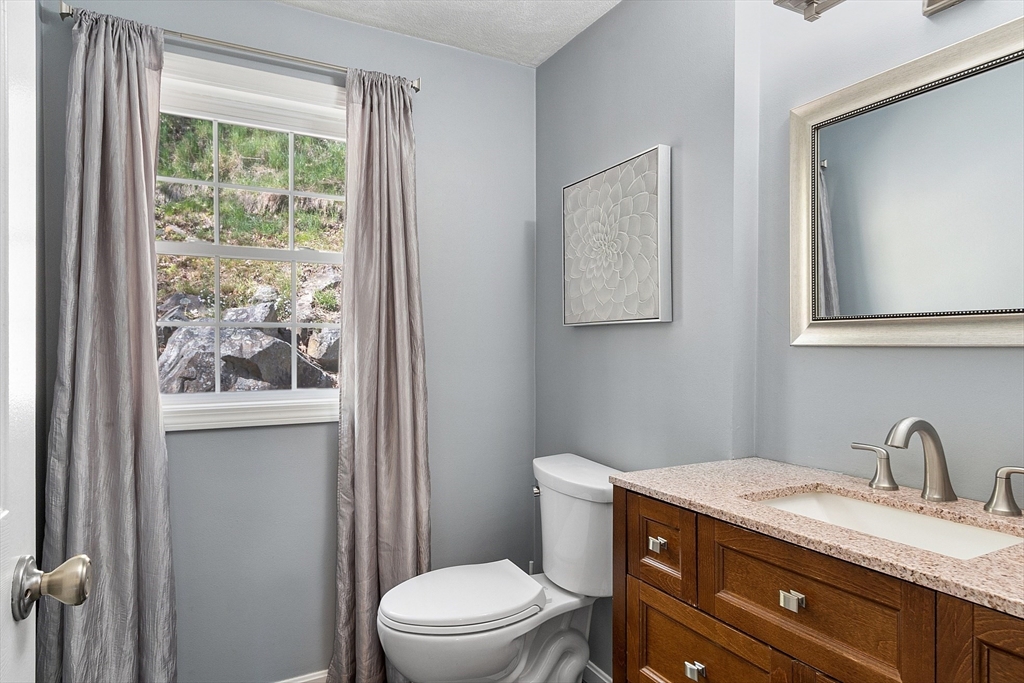 10 Station Road Salem, MA 01970 - Photo 22 of 37 a bathroom with a granite countertop toilet a sink a mirror and window