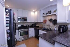 2388 Royal Avenue, Unit 26 Simi Valley, CA 93065 - Photo 3 of 11 a kitchen with stainless steel appliances granite countertop a sink a stove and a microwave