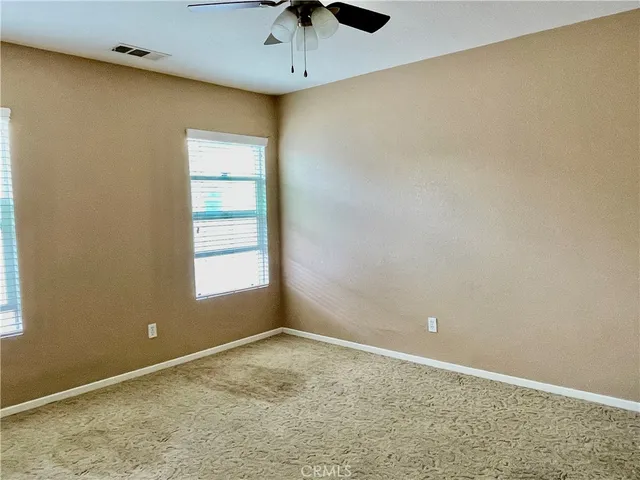 an empty room with a window and a ceiling fan