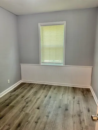 an empty room with wooden floor and entrance
