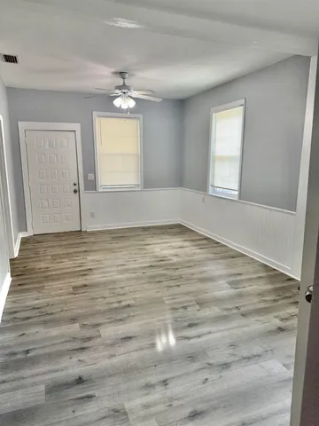 a view of an empty room with wooden floor and a window