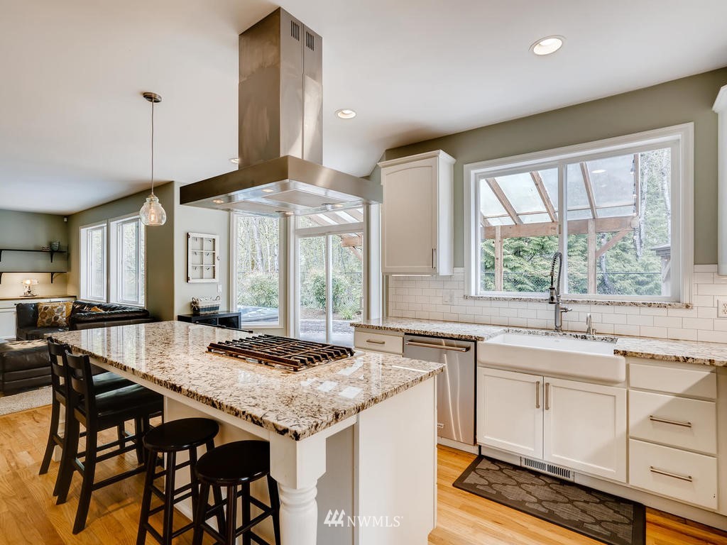 18718 Southeast 144th Street Renton, WA 98059 - Photo 4 of 25 a open kitchen with granite countertop a stove a sink and white cabinets with wooden floor