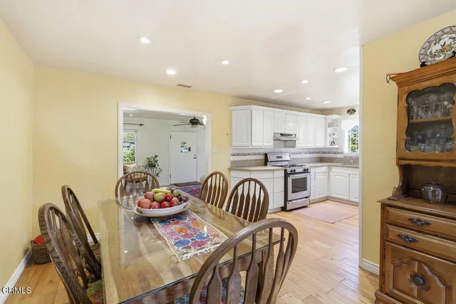 a kitchen with stainless steel appliances granite countertop a dining table chairs and a refrigerator