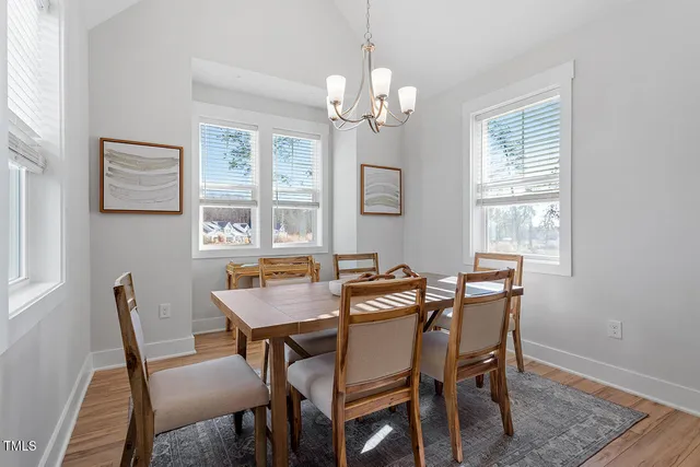 a view of a dining room with furniture a chandelier and wooden floor