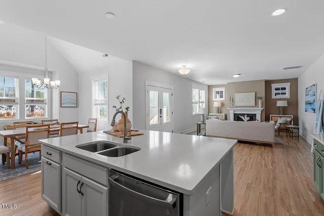 a kitchen with stainless steel appliances a table chairs sink and cabinets