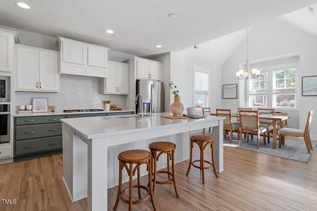 a kitchen with stainless steel appliances granite countertop a table chairs sink refrigerator and cabinets
