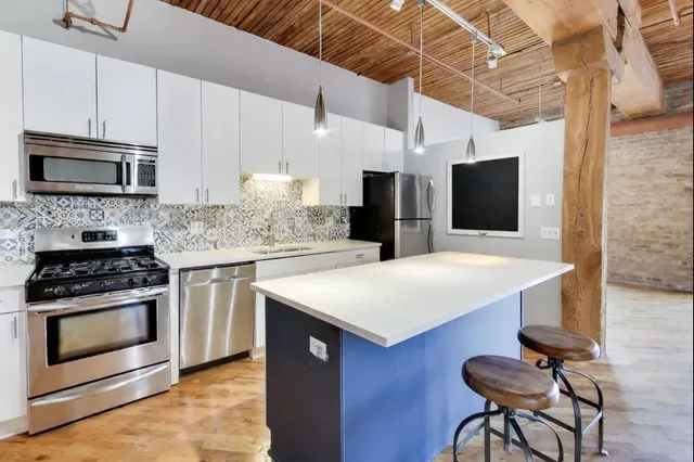 a kitchen with stainless steel appliances a stove a microwave and white cabinets