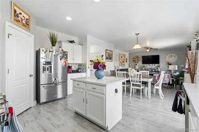a kitchen with stainless steel appliances granite countertop a refrigerator and a dining table