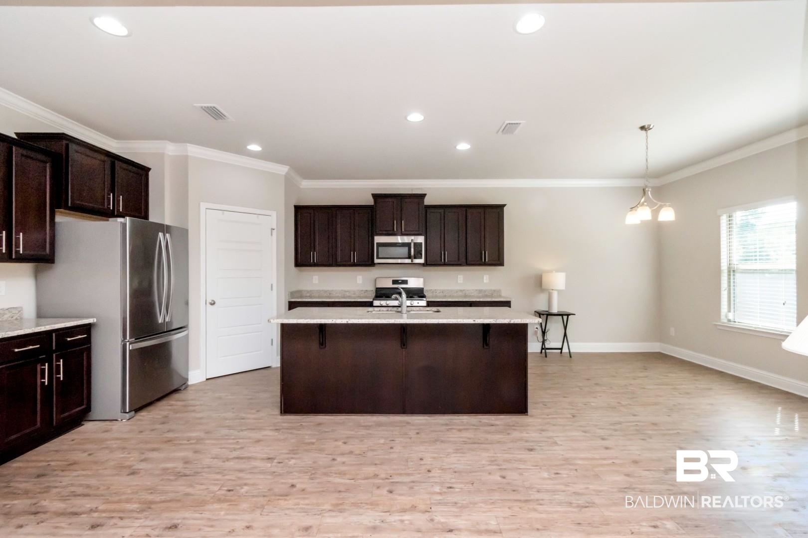 1282 Creek Ridge Court Mobile, AL 36695 - Photo 9 of 33 Kitchen with dark brown cabinets, crown molding, a breakfast bar area, decorative light fixtures, and light wood-style flooring