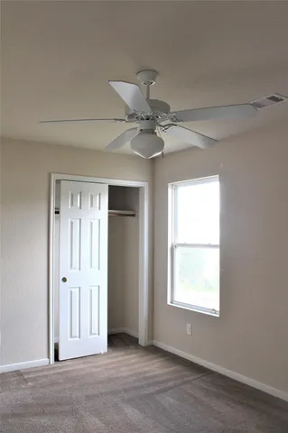 an empty room with a window and a ceiling fan